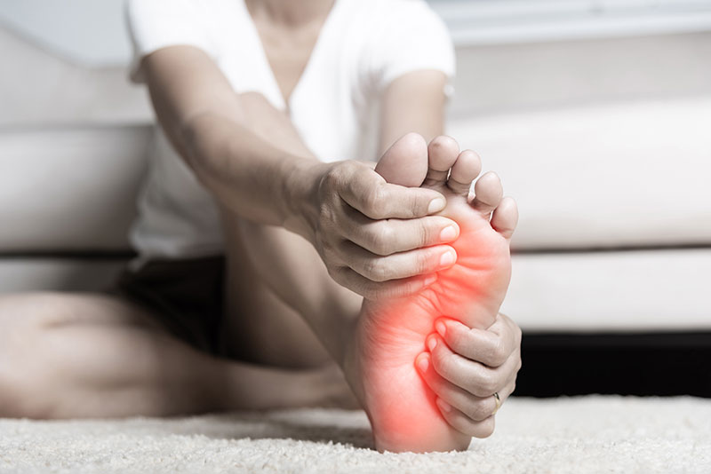 person holding their foot that is highlighted in red to indicate pain