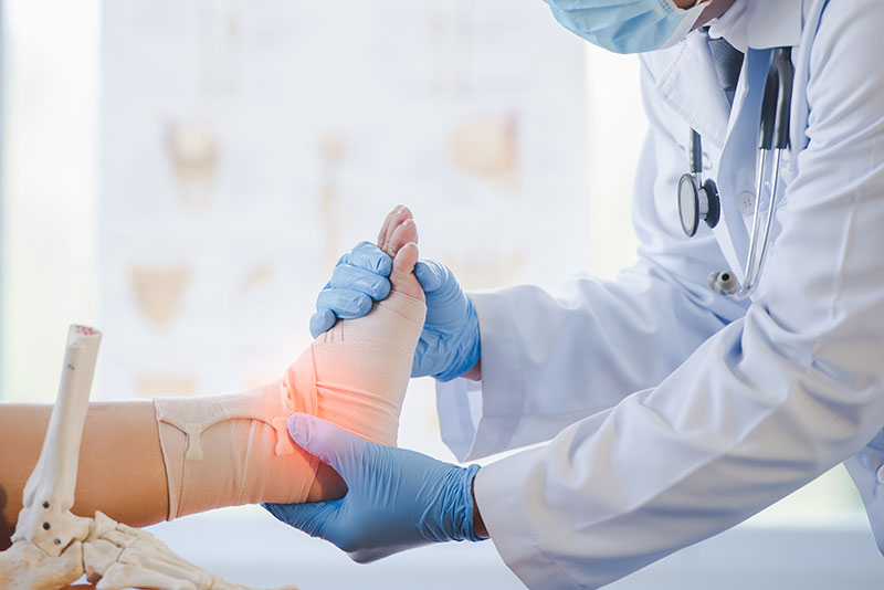 doctor assessing a patient's foot wearing an ankle bandage